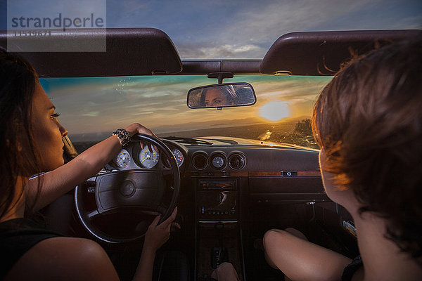 Zwei junge Frauen in einem Cabriolet  Fahrt auf einer Panoramastraße  Rückansicht