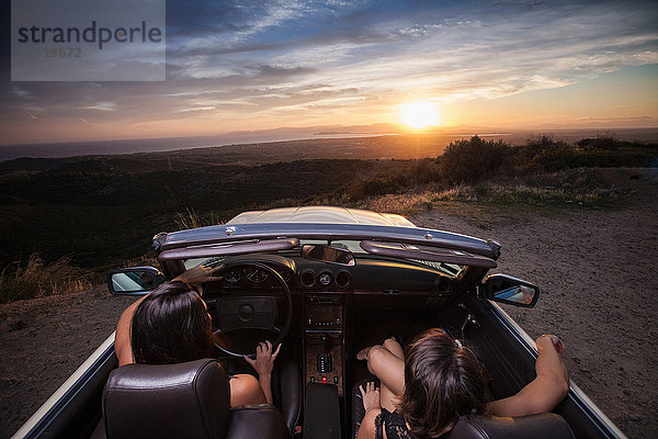 Zwei junge Frauen in einem Cabriolet  Fahrt auf einer Panoramastraße  Rückansicht