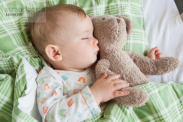 Draufsicht auf einen schlafenden Jungen mit Teddybär im Bett