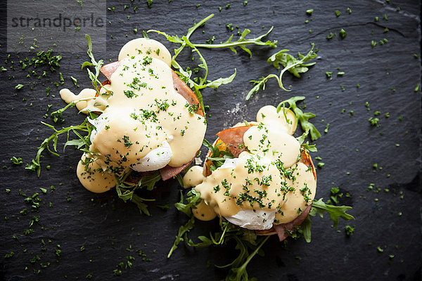 Draufsicht auf die Sauce Hollandaise mit Eiern Benedikt-Frühstück auf Schiefer