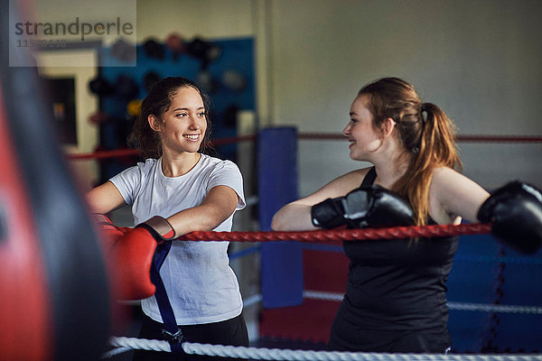 Junge Boxerinnen lehnen sich an Boxring-Seile an und unterhalten sich