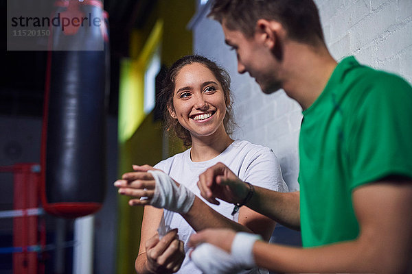 Junge männliche und weibliche Boxer unterhalten sich beim Bandagieren der Hände