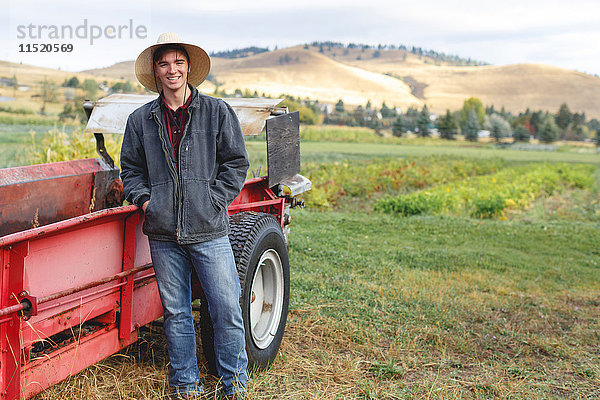 Porträt eines jungen Mannes neben einem Traktor stehend  Missoula  Montana  USA