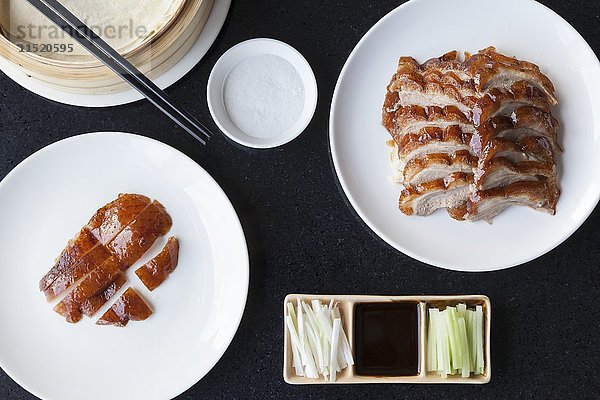 Scheiben von knuspriger Peking-Ente und Entenhaut mit Pfannkuchen  Frühlingszwiebeln  Gurken und Hoisin-Sauce