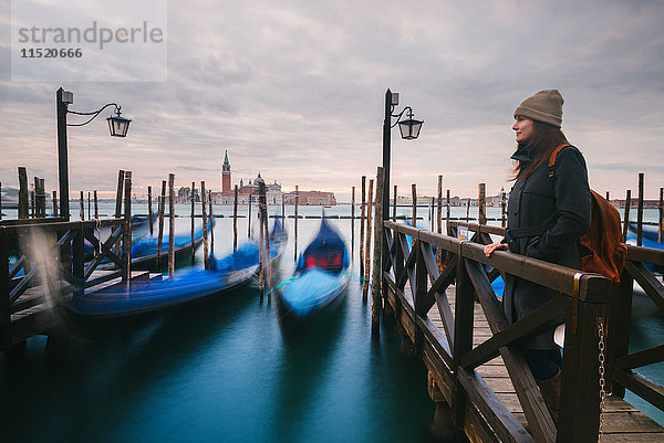 Frau auf dem Pier mit Gondeln im Canal Grande  Insel San Giorgio Maggiore im Hintergrund  Venedig  Italien