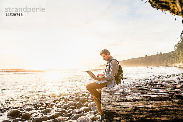 Mann sitzt mit Laptop am Strand im Juan de Fuca Provincial Park  Vancouver Island  British Columbia  Kanada