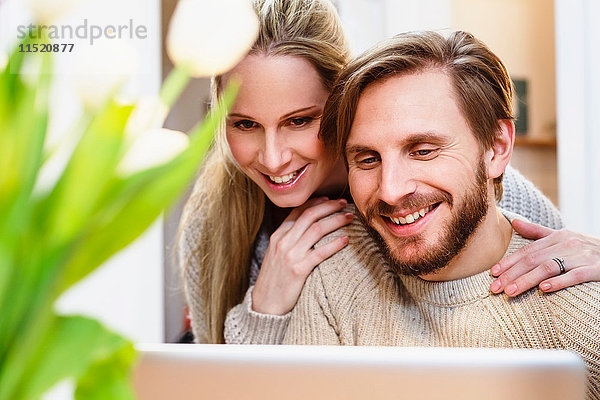 Mittleres erwachsenes Paar  das gemeinsam in der Küche auf den Laptop schaut