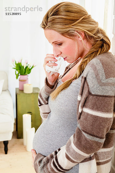 Tränenreiche schwangere Frau berührt Bauch im Wohnzimmer