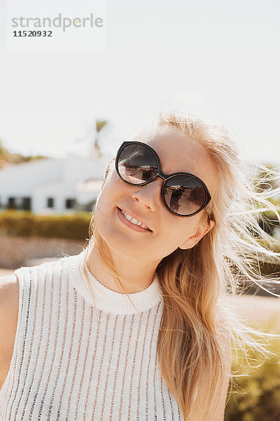 Porträt einer Frau mit Sonnenbrille  die lächelnd in die Kamera schaut