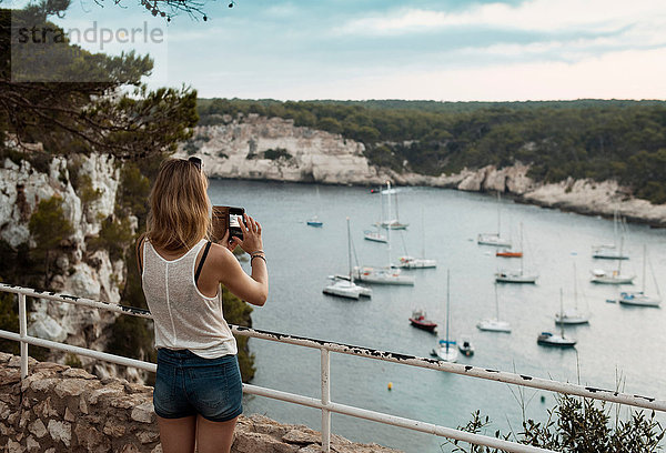 Frau fotografiert Hafen mit Smartphone  Menorca  Spanien