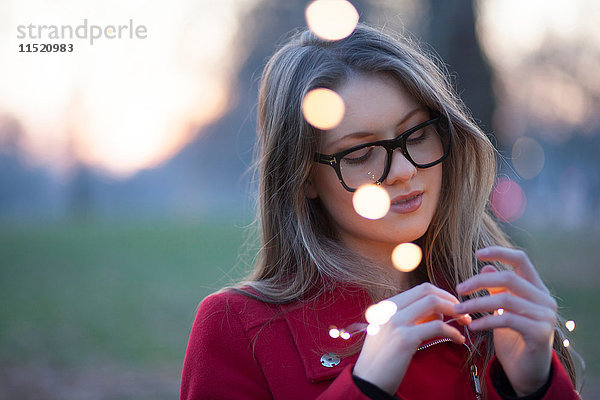 Junge Frau im Park mit Blick auf Lichter in der Hand  London  UK