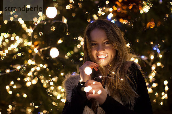 Junge Frau mit Licht in der Hand  Baum im Hintergrund