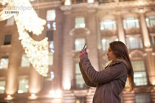 Junge Frau fotografiert Weihnachtsbeleuchtung  Regent Street  London  UK