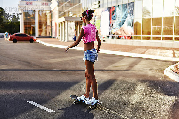 Junge Frau beim Skateboarden entlang der Straße  Rückansicht
