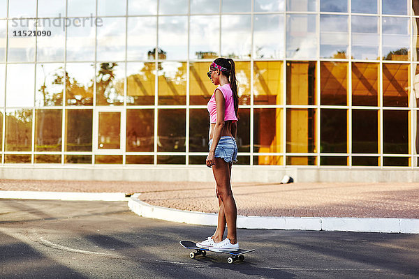 Junge Frau fährt Skateboard entlang der Straße