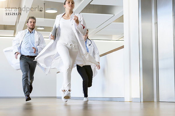 Männliche und weibliche Ärzte entlang des Krankenhauskorridors
