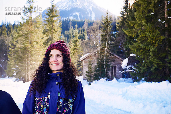 Frau mit Strickmütze beim Blick durch den verschneiten Wald  Österreich