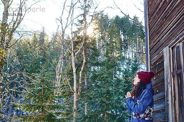 Frau mit Strickmütze praktiziert Yoga  Meditation im Blockhaus