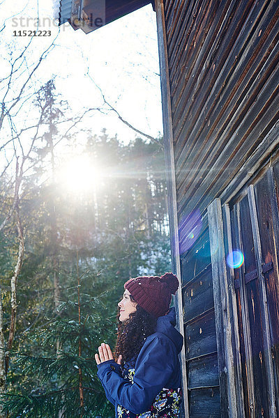 Frau mit Strickmütze praktiziert Yoga  Meditation im Blockhaus