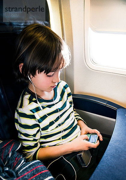 Junge im Flugzeug wählt Musik auf mp3-Player