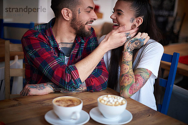 Paar im Café von Angesicht zu Angesicht lächelnd