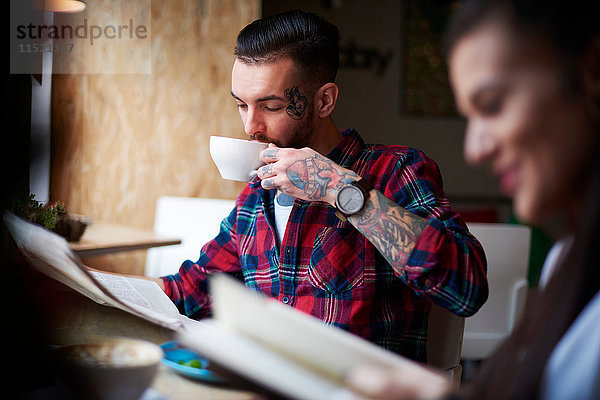 Paar trinkt Kaffee und liest Zeitungen