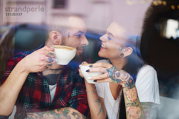 Blick durch das Fenster eines Pärchens im Café von Angesicht zu Angesicht lächelnd