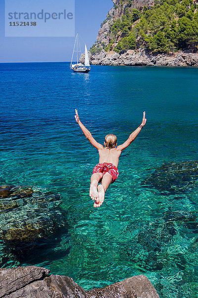 Rückansicht eines jungen Mannes  der ins Meer taucht  Cala Tuent  Mallorca  Spanien