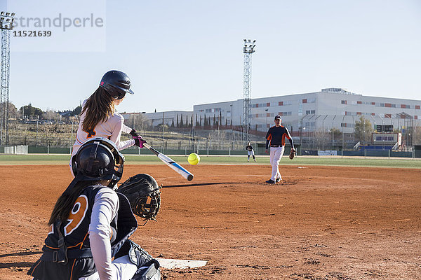 Weiblicher Teig  der den Ball während eines Baseballspiels trifft.