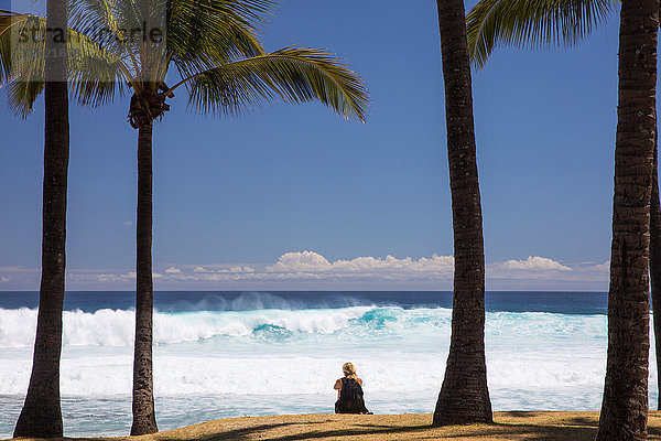 Touristin sitzt am Strand mit Blick auf den Indischen Ozean  Insel Réunion