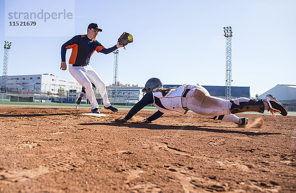 Baseballspieler  der während eines Baseballspiels zur Basis rutscht.
