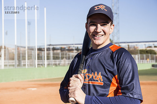 Porträt eines lächelnden Baseballspielers mit Baseballschläger