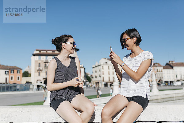 Italien  Padua  junge Frau beim Fotografieren ihrer Freundin mit dem Smartphone