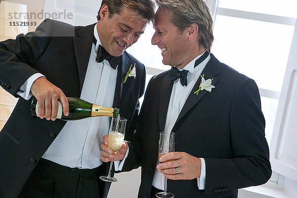 Frisch verheiratetes  reifes  männliches Paar schenkt Champagner ein