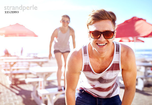 Porträt eines Mannes mit Sonnenbrille  der lächelnd in die Kamera schaut