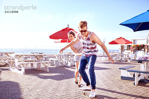 Paar mit Skateboard auf der Promenade