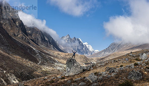 Nepal  Himalaya  Khumbu  Everest-Region  Khunde  Frau jubelnd auf Felsen