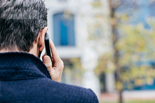 Rückansicht eines Mannes bei der Benutzung eines Mobiltelefons