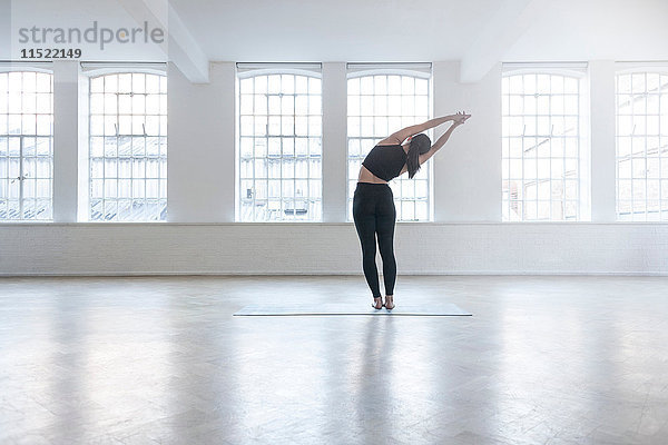 Rückansicht einer Frau im Tanzstudio beim Stretching