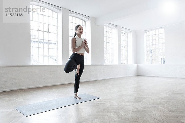 Frau im Tanzstudio auf einem Bein stehend in Yogastellung