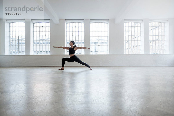 Frau im Tanzstudio in Yogastellung