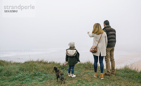 Familie mit Hund an der Küste an einem nebligen Wintertag mit Blick auf die Landschaft