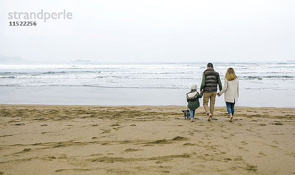Familienwanderung mit Hund am Strand im Winter