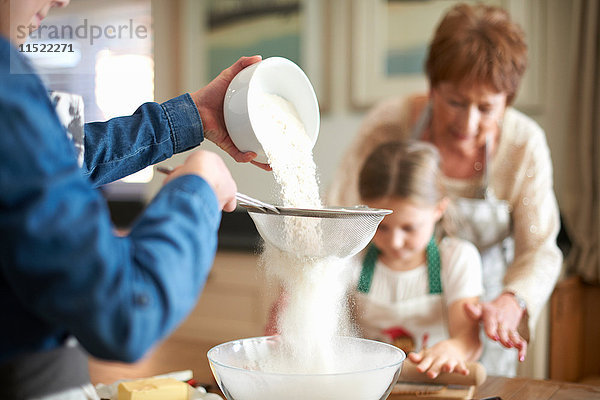 Ältere Frau und Enkelinnen sieben Mehl für Kekse
