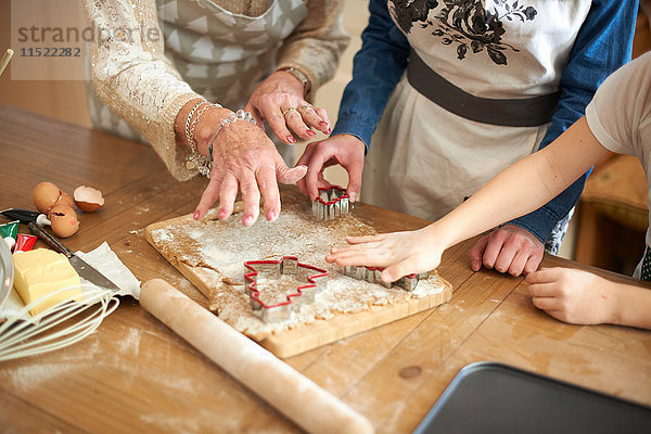Schnappschuss einer älteren Frau und Enkelinnen beim Schneiden von Weihnachtsbaumplätzchen an der Küchentheke