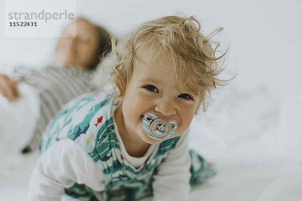 Porträt eines glücklichen kleinen Mädchens mit Mutter im Bett