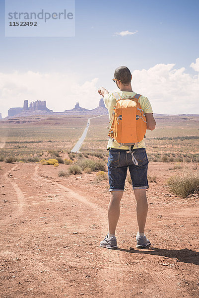 USA  Utah  Rückansicht des Mannes mit Rucksack  der auf Monument Valley zeigt
