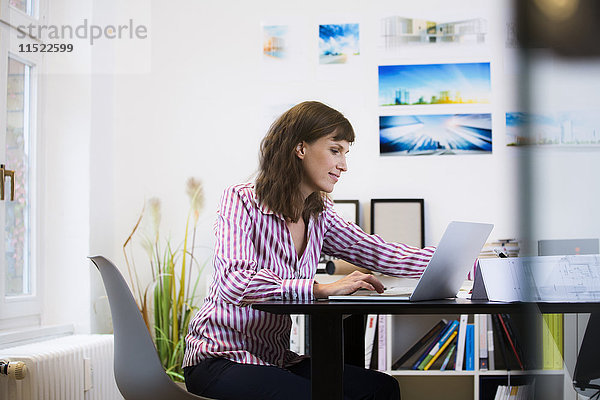 Lächelnde Frau mit Laptop im Büro