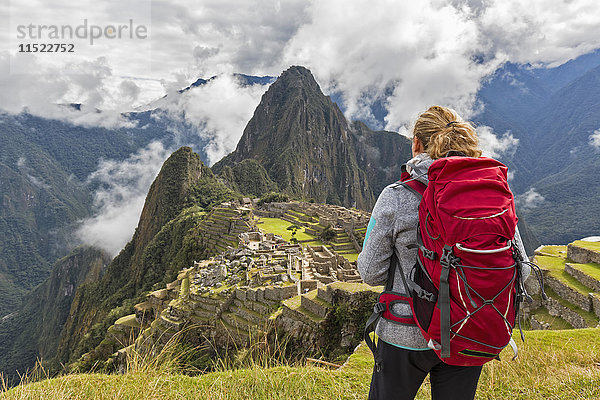 Peru  Anden  Urubamba-Tal  Tourist mit rotem Rucksack bei Machu Picchu mit Berg Huayna Picchu