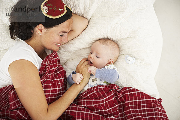 Lächelnde Mutter und Baby im Bett liegend